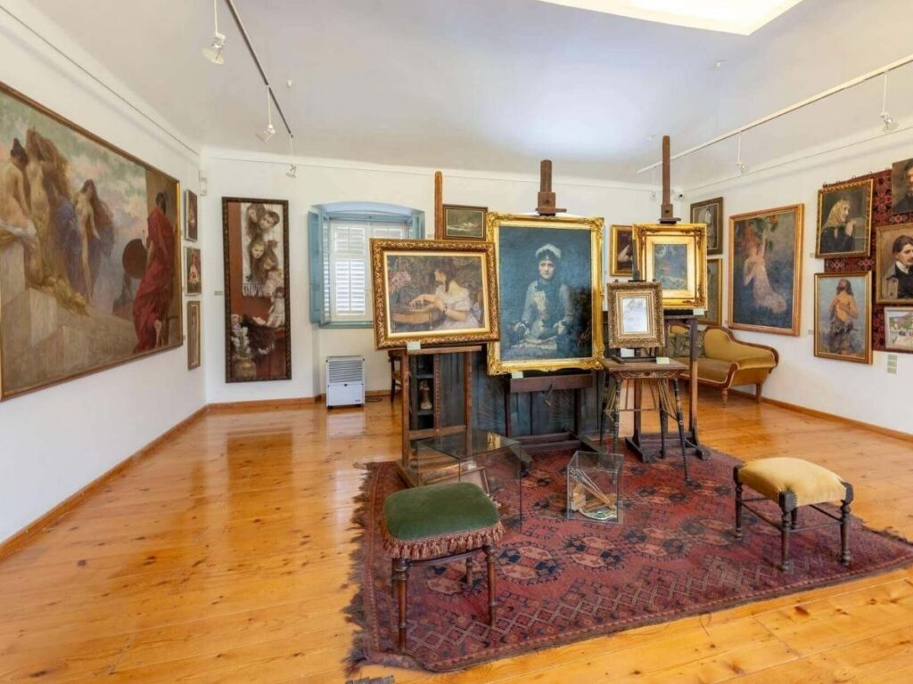 Interior of Bukovac House showing a painter’s studio wall covered in sketches and sunlight through lace curtains