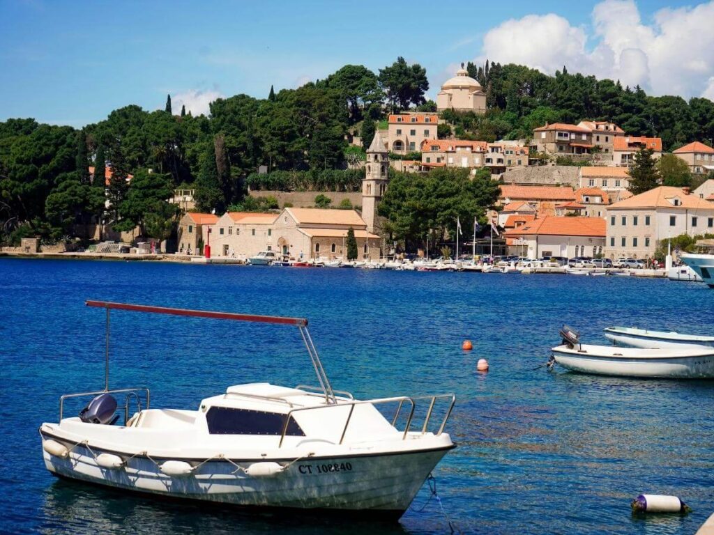 Outdoor table at a seaside restaurant in Cavtat with plates of grilled fish and glasses of chilled white wine overlooking the harbour