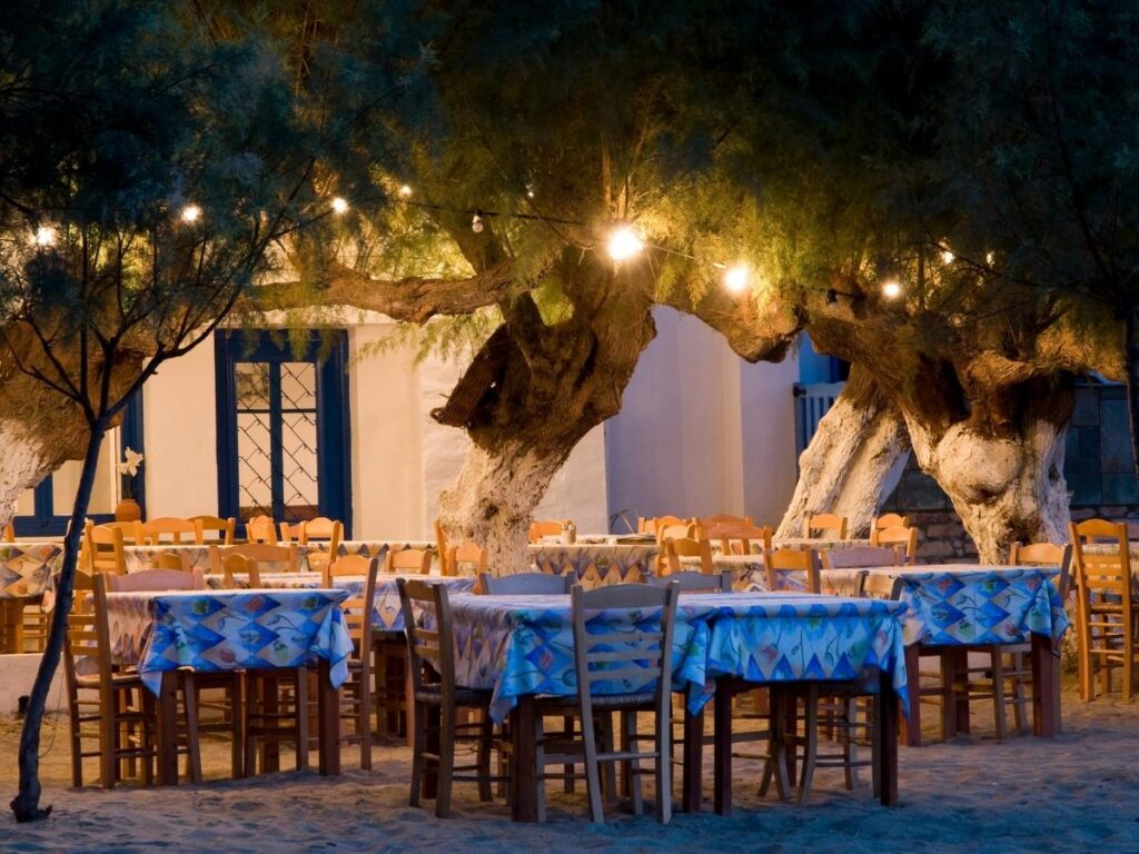 Evening scene in Chora square with tavernas, candlelit tables and fairy lights, Folegandros