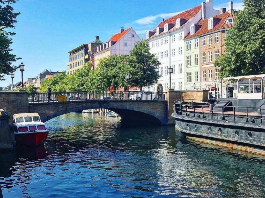 Sightseeing boat gliding under bridges along the canals of Copenhagen