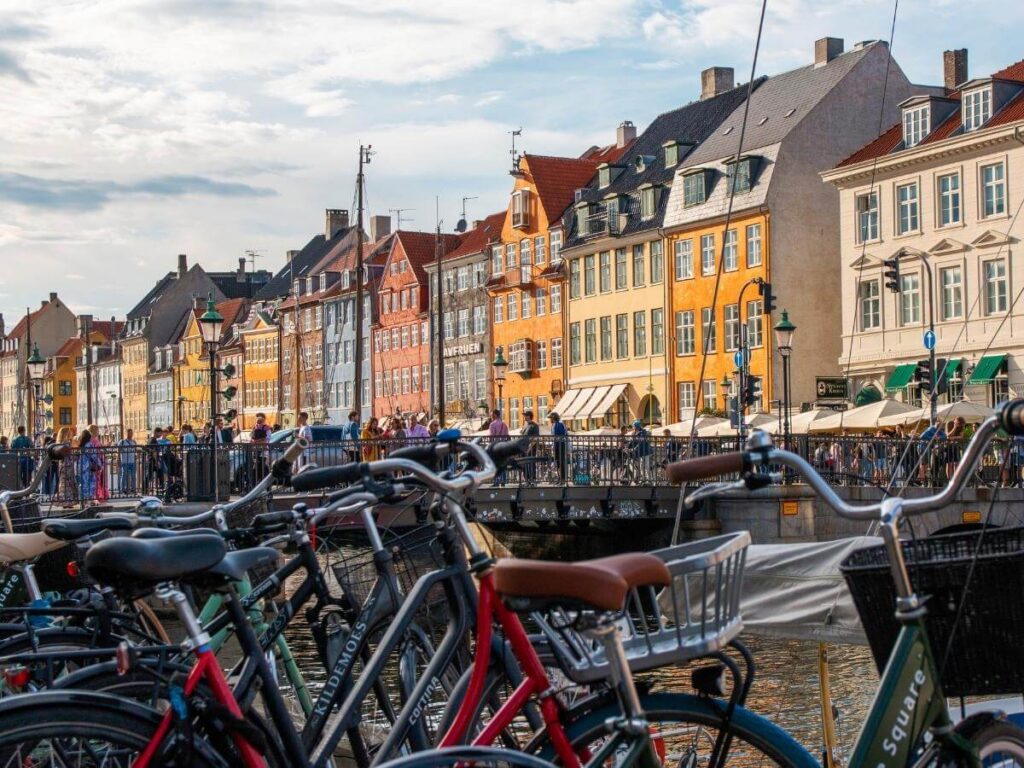 Early morning mist over Copenhagen canals with cyclists passing and pastel houses in the background.