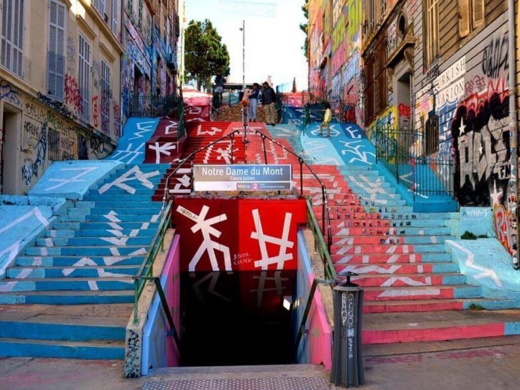 Bold street art mural on a wall in Cours Julien with passersby and a café in the foreground