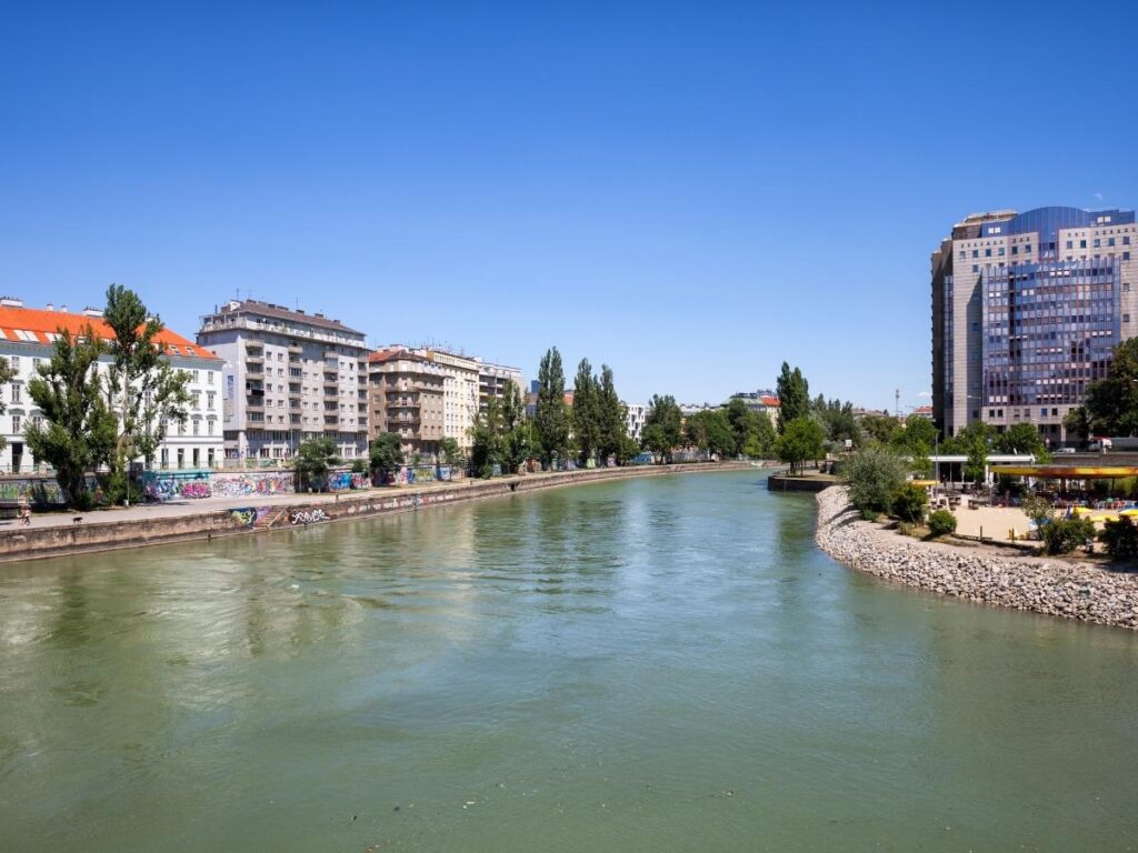 Strollers and cafés along the Danube Canal at sunset with colourful street art