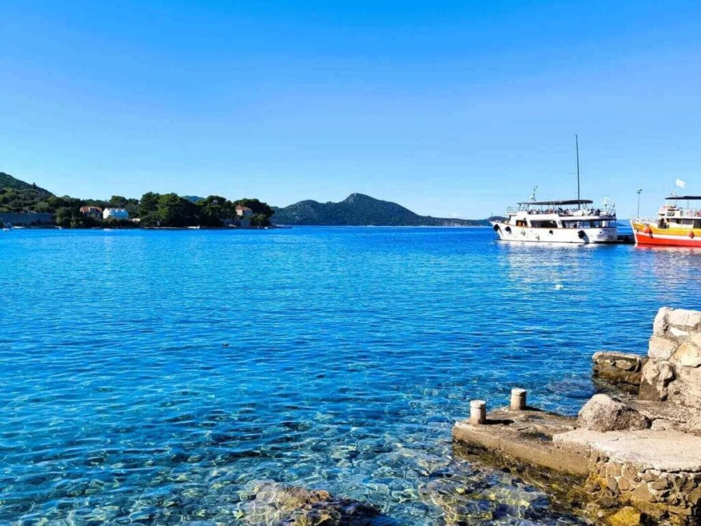 Small tourist boat anchored in a turquoise cove on the Elaphiti Islands