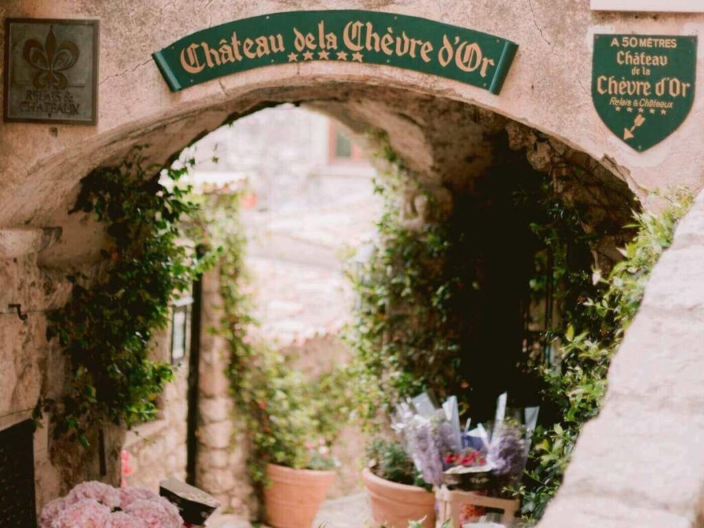Stone archway at the entrance of Èze Village with cobbled lanes and climbing plants