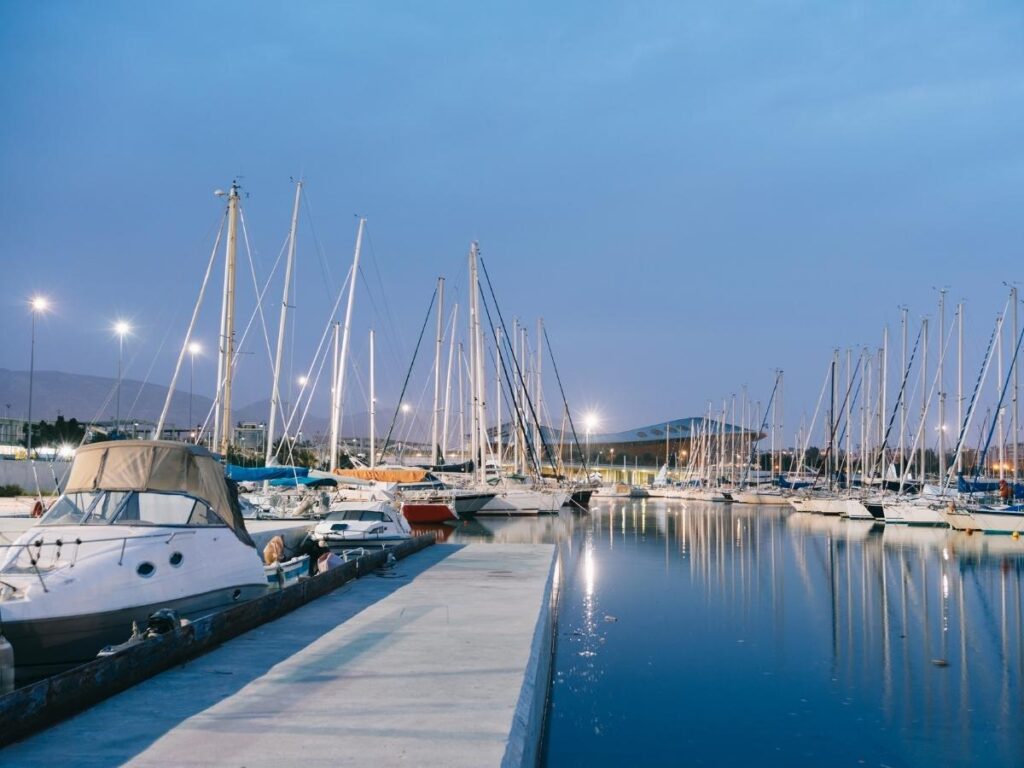 Families strolling along Flisvos Marina with yachts moored under a blue sky