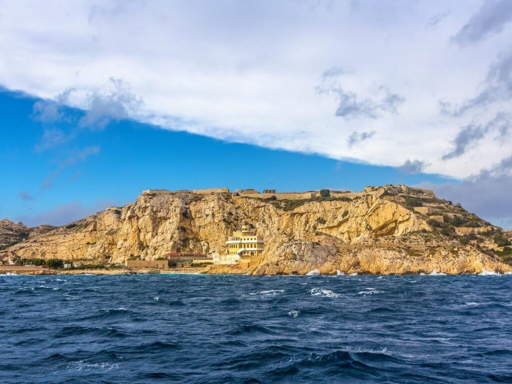 A quiet pebble cove on the Frioul Islands with clear shallow water and a rocky shoreline