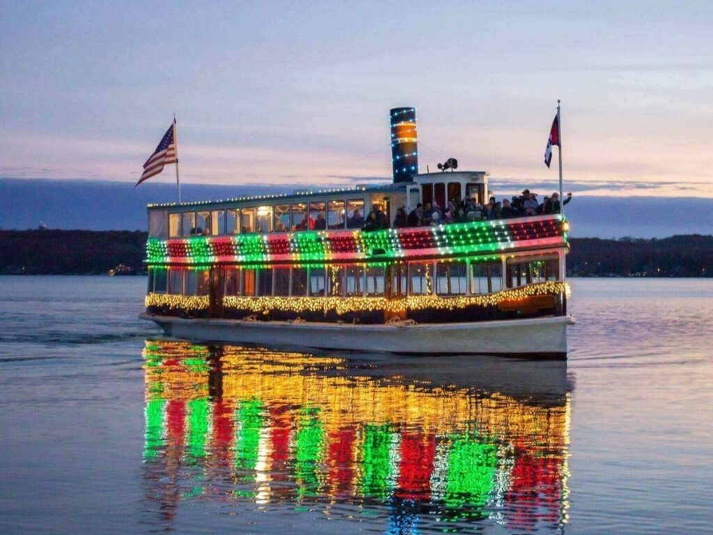 Passengers on the deck of a boat cruising Lake Geneva with mountains in the distance