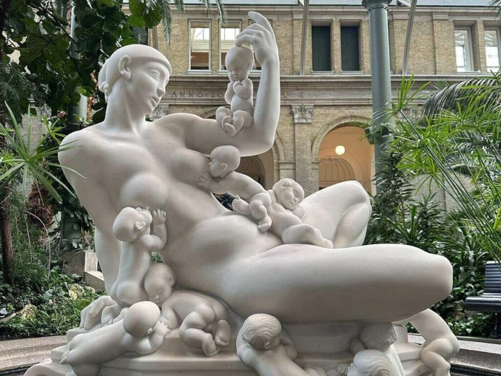 Palm trees and sculptures inside the glass-domed winter garden at Glyptoteket Museum, Copenhagen.
