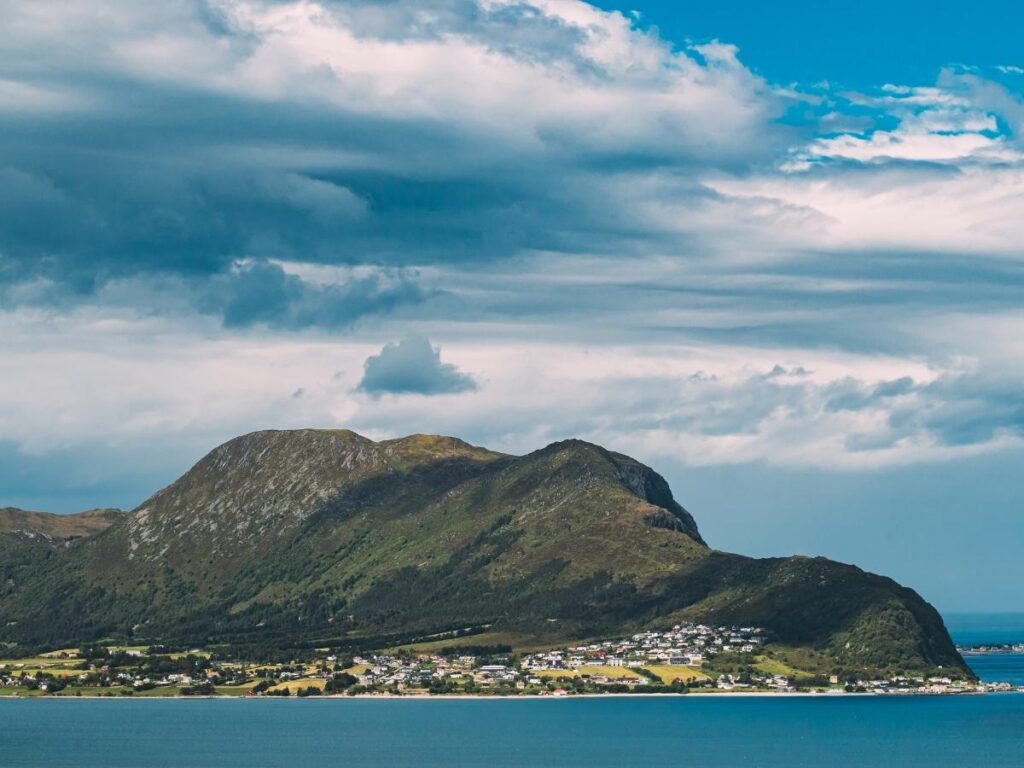 Hiker on Storhornet summit with sweeping island and sea views near Ålesund