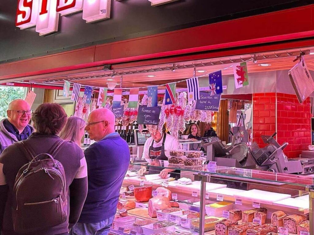 Food stalls with cheese, seafood, and charcuterie inside Halles Paul Bocuse in Lyon