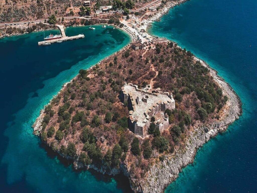Stone houses of Himarë with the castle above and the sunset glow over the bay