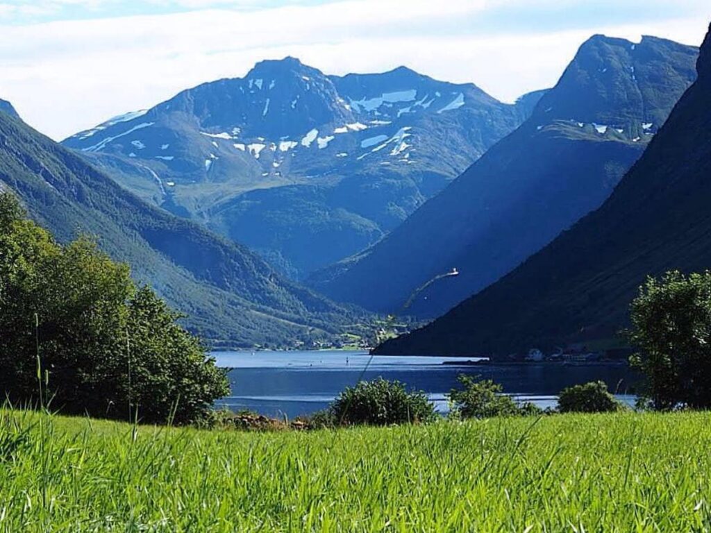 Small cruise boat moving through the steep-sided Hjørundfjord near Ålesund