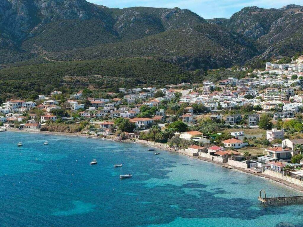 Small tour boat entering a sea cave on the Karaburun Peninsula with steep limestone cliffs