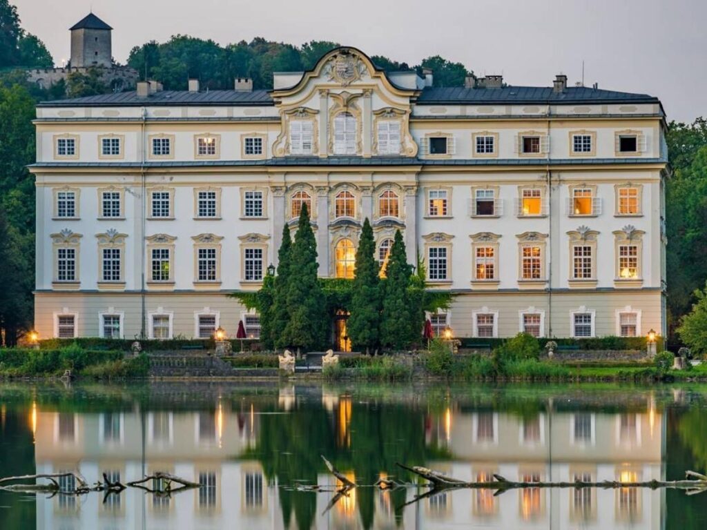 Leopoldskron Palace reflected in the calm lake with mountain backdrop