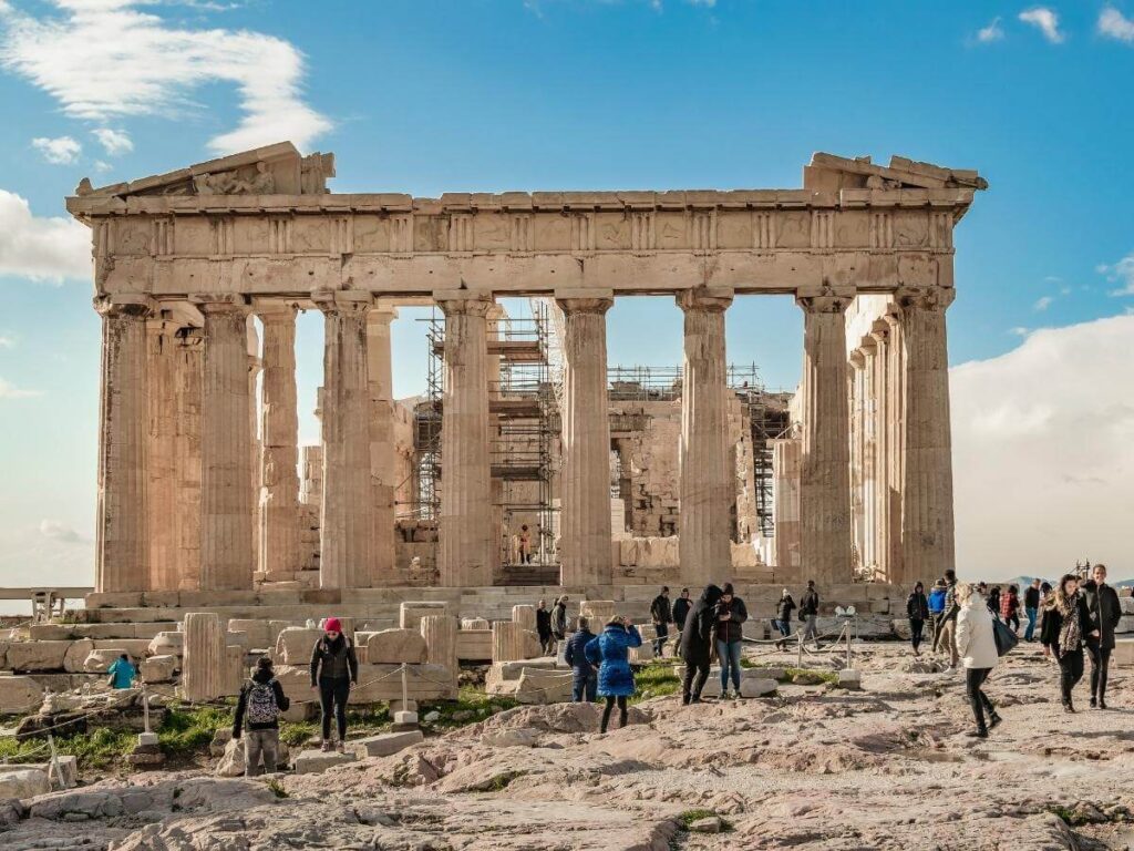 A visitor climbing the worn marble steps toward the Parthenon, early morning shadows stretching across the hill