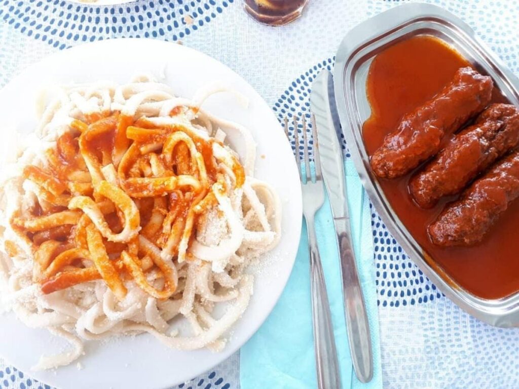 Close-up of matsáta handmade pasta with sauce — traditional Folegandros dish on a ceramic plate