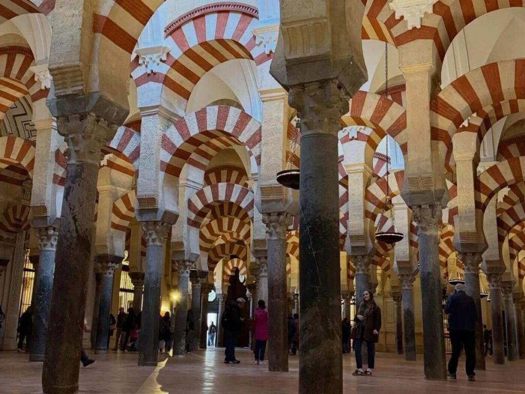 Close-up vertical shot of the Mezquita’s red-and-white arches leading into shadow