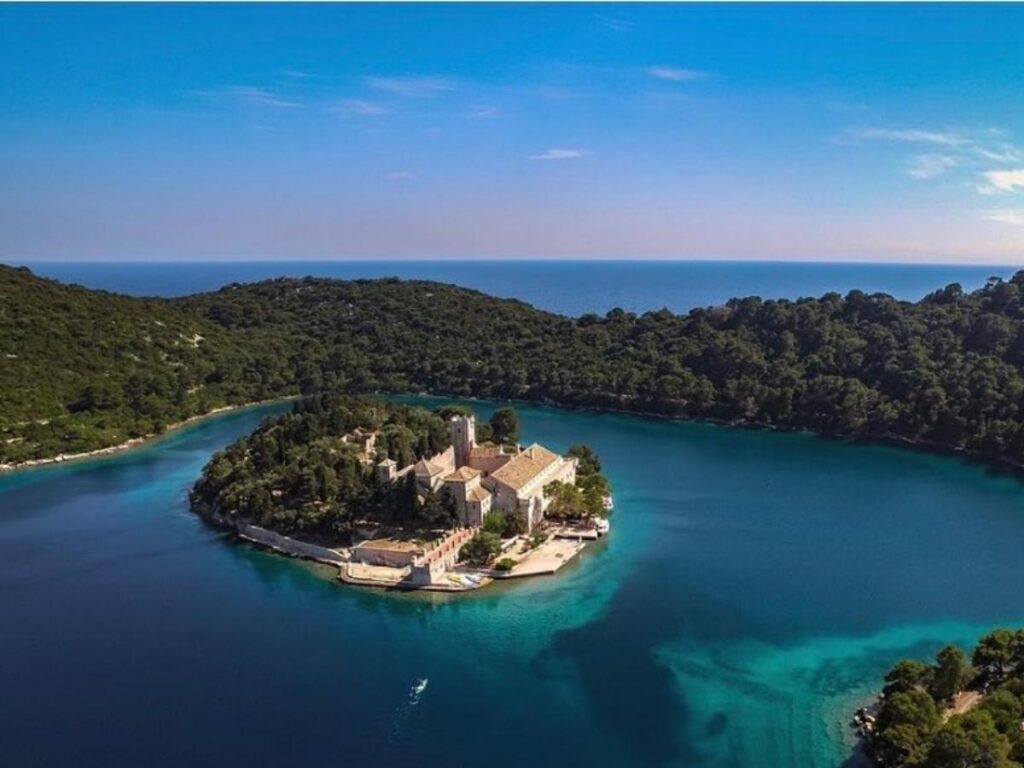 Empty lakeside path in Mljet National Park at dusk, shaded by pine trees