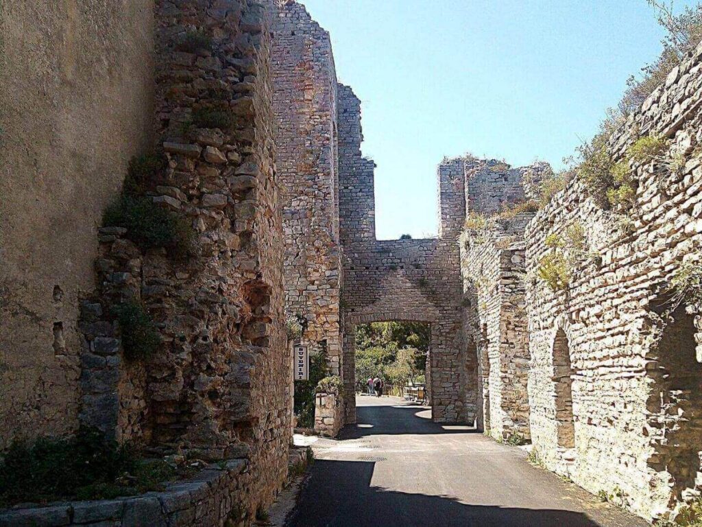 Ancient Roman ruins rising above Polače harbour, with fishing boats moored in the foreground