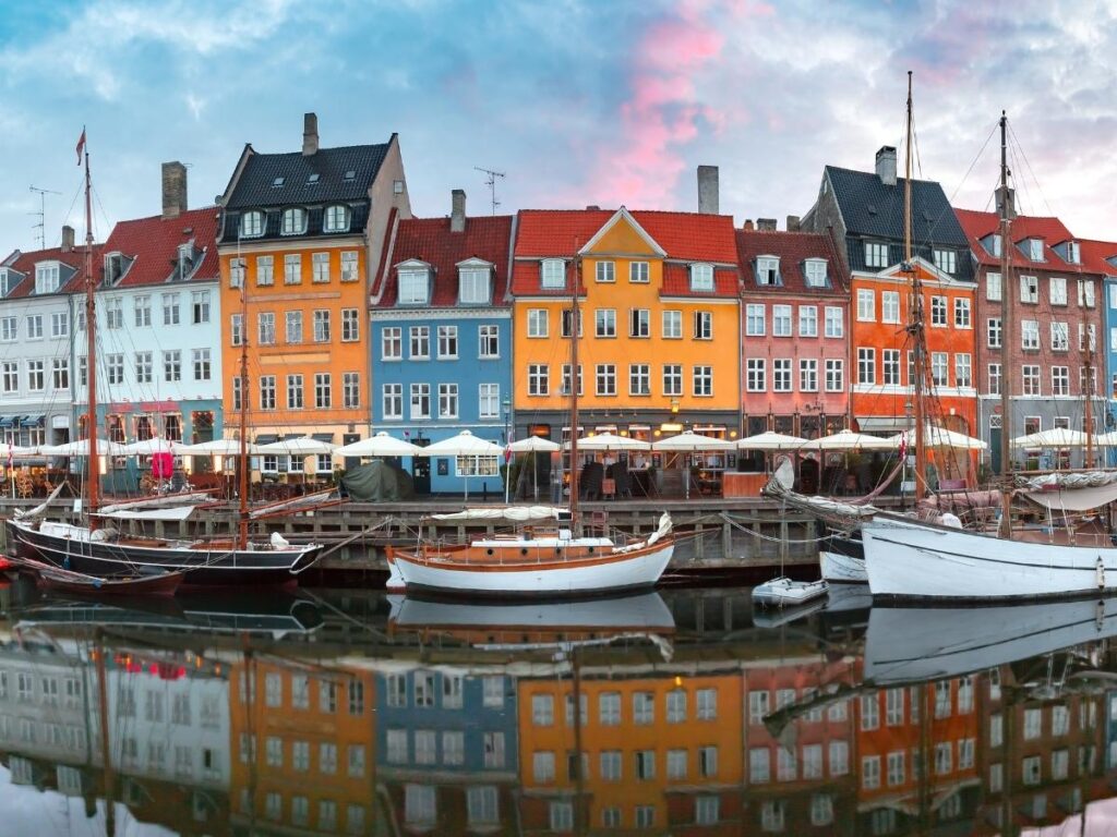 Early morning light over Nyhavn canal with colorful buildings and boats in Copenhagen.