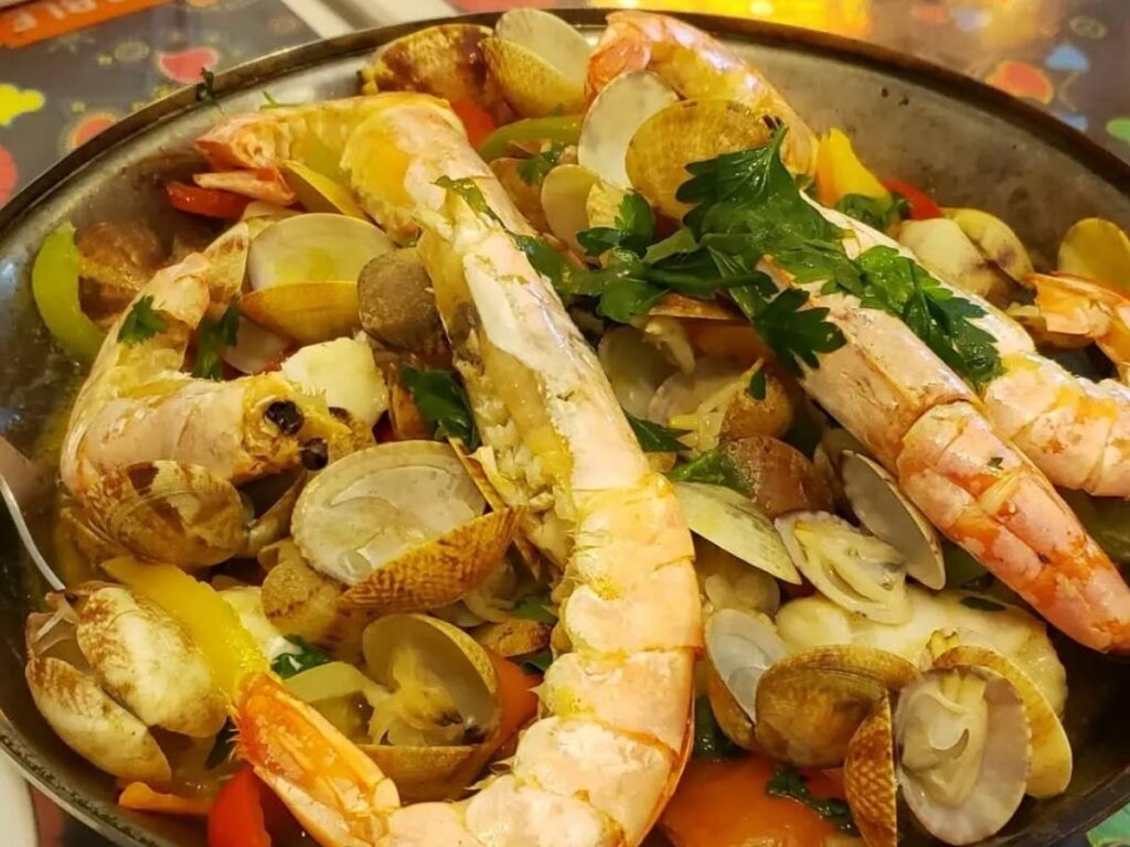 Grilled sardines and sea bream on a smoky charcoal grill at a local tasca in Olhão, Portugal