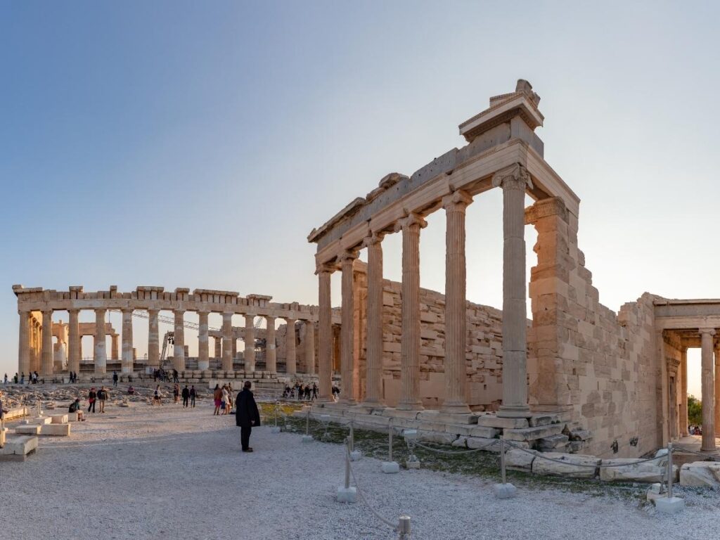 The Parthenon and Erechtheion standing side by side on the Acropolis under bright morning sky.