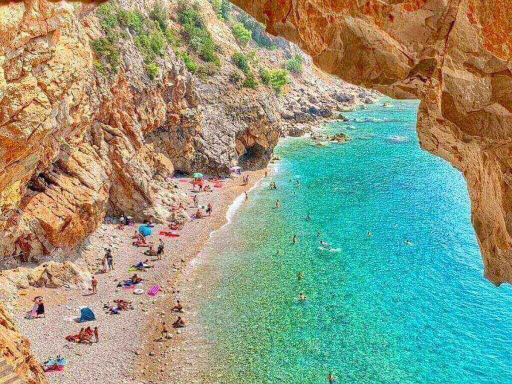 Dramatic view down the cliff staircase to Pasjača Beach and a tiny turquoise cove framed by steep rock walls