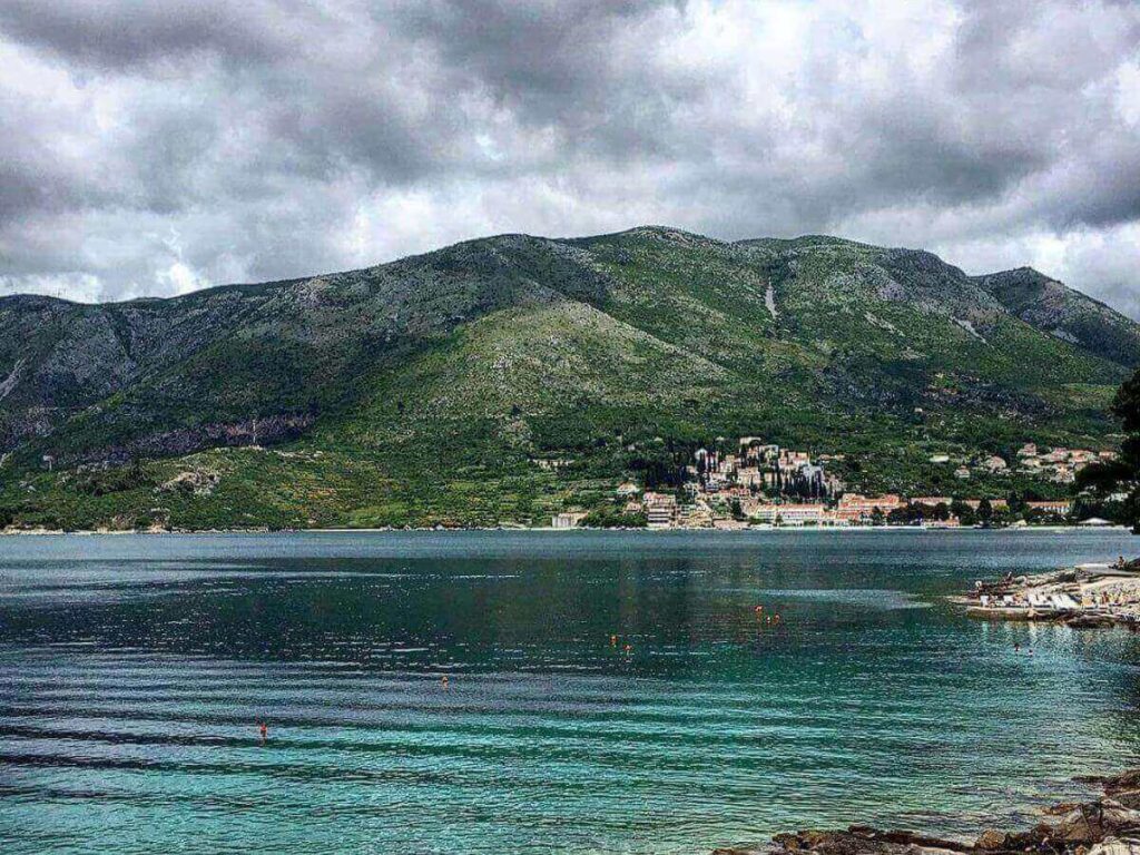 Pine-shaded coastal path on the Rat Peninsula leading to a small white lighthouse at the tip