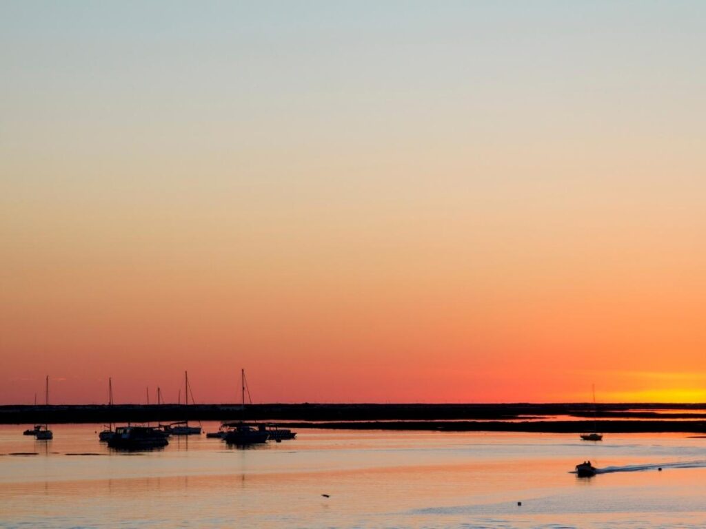 Small fishing boats resting in shallow water at sunset with golden reflections, Ria Formosa lagoon