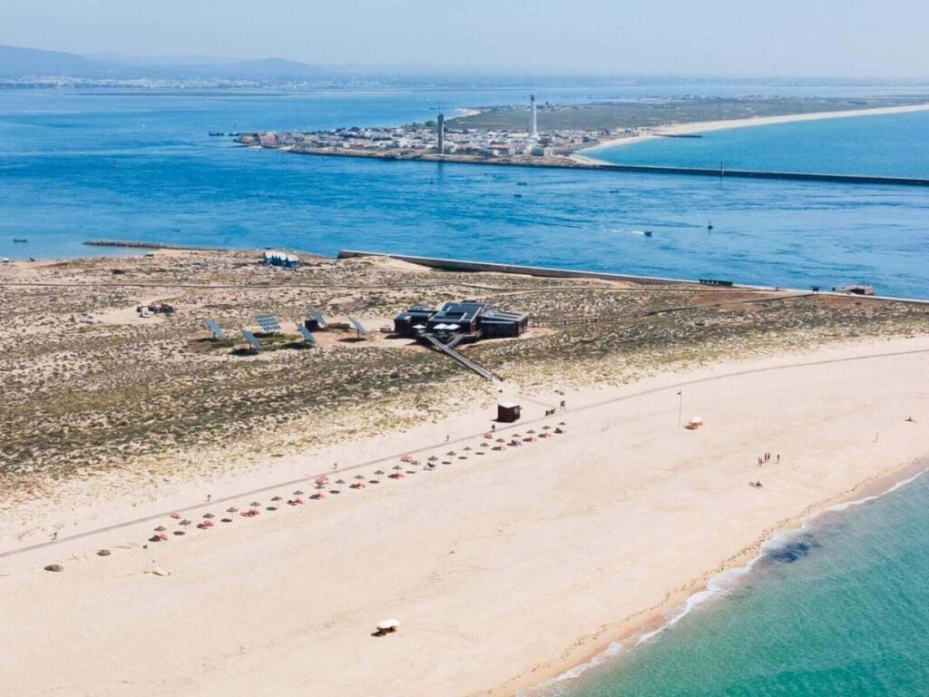 Empty white-sand beach on Ilha Deserta with clear turquoise sea and dunes, Ria Formosa