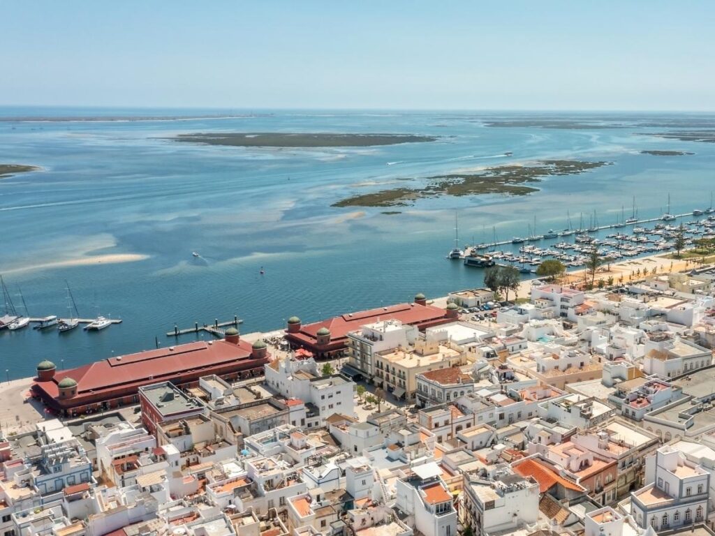 Public ferry leaving Olhão marina with salt pans and lagoon in the background, Ria Formosa