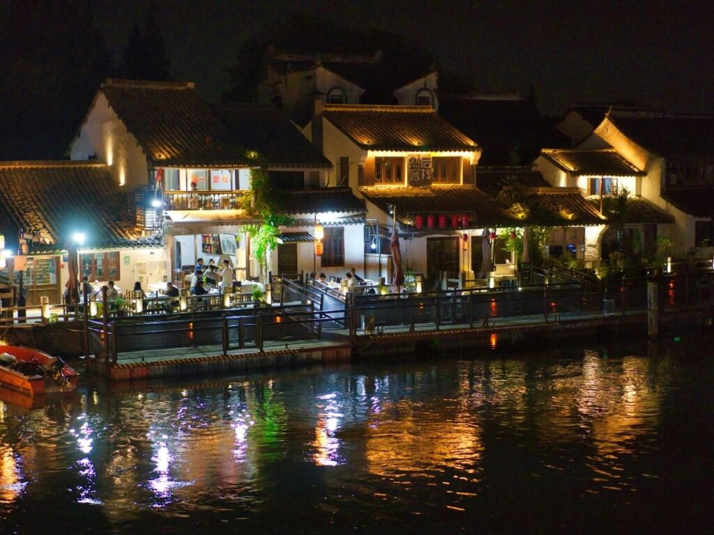 Riverside restaurant terrace glowing with lights and reflections on the Salzach at night