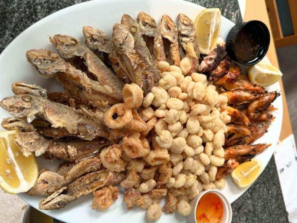 Grilled whole fish on a plate with lemon wedges and olive oil, served at a Sarandë harbour restaurant