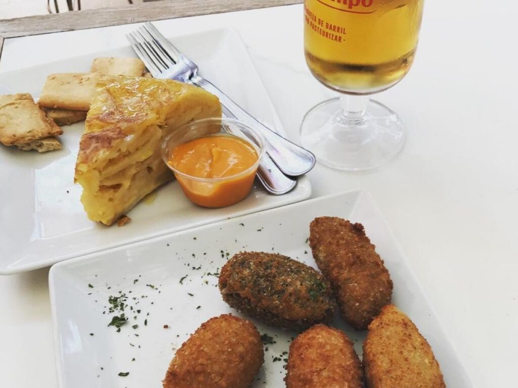 Slice of Spanish tortilla and a bowl of chilled salmorejo on a café table