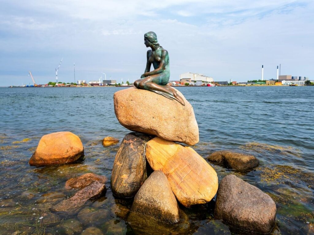 The Little Mermaid statue near the Kastellet fortress on a sunny day in Copenhagen.