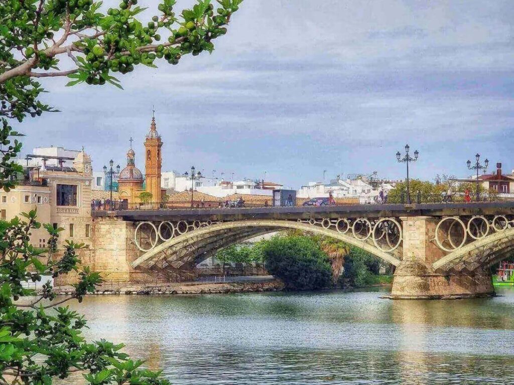 Riverside evening in Triana with reflections and people strolling