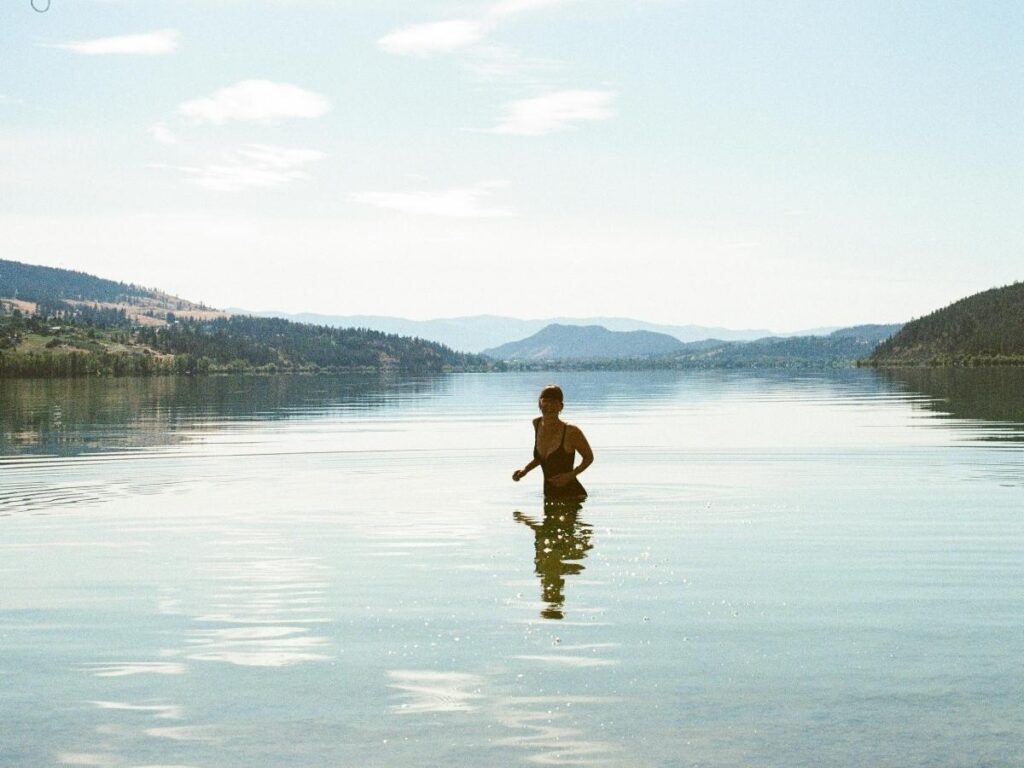 Person floating in the warm, sheltered waters of Vouliagmeni Lake with cliffs behind