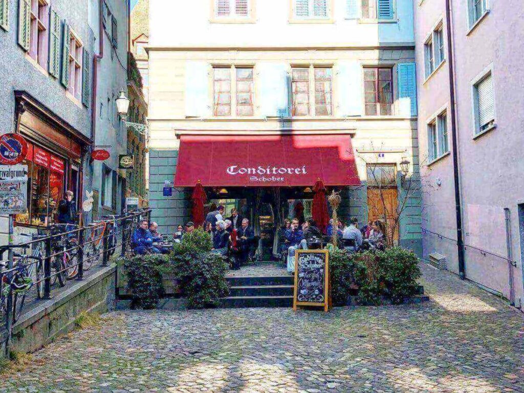 Narrow cobblestone street in Zurich’s Old Town with cafés and small shops