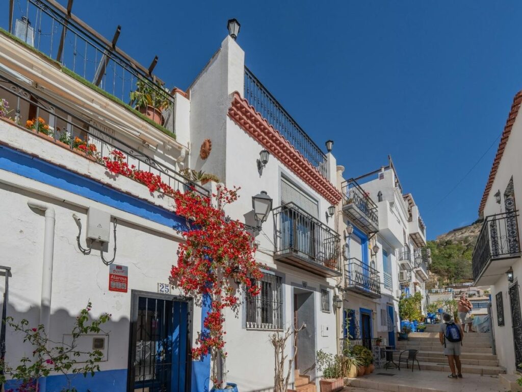 Narrow whitewashed street in Córdoba’s Jewish Quarter lined with flowerpots and traditional balconies