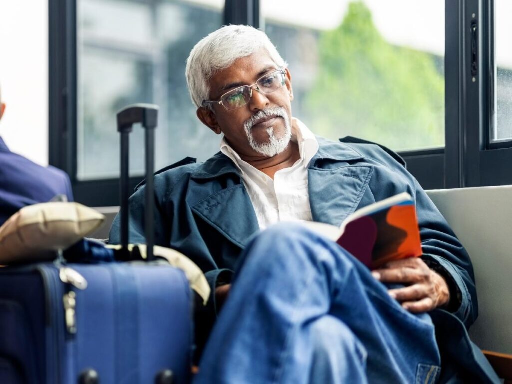 Traveler enjoying coffee and reading book at airport cafe before flight