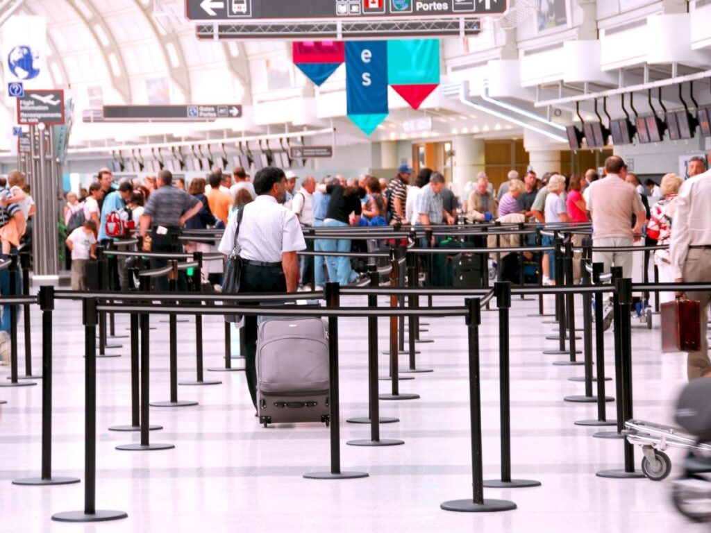 Crowded airport security checkpoint with travelers waiting in long lines