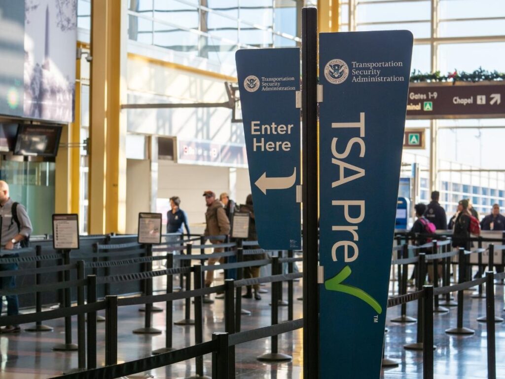 Traveler checking TSA wait times on mobile app at airport security