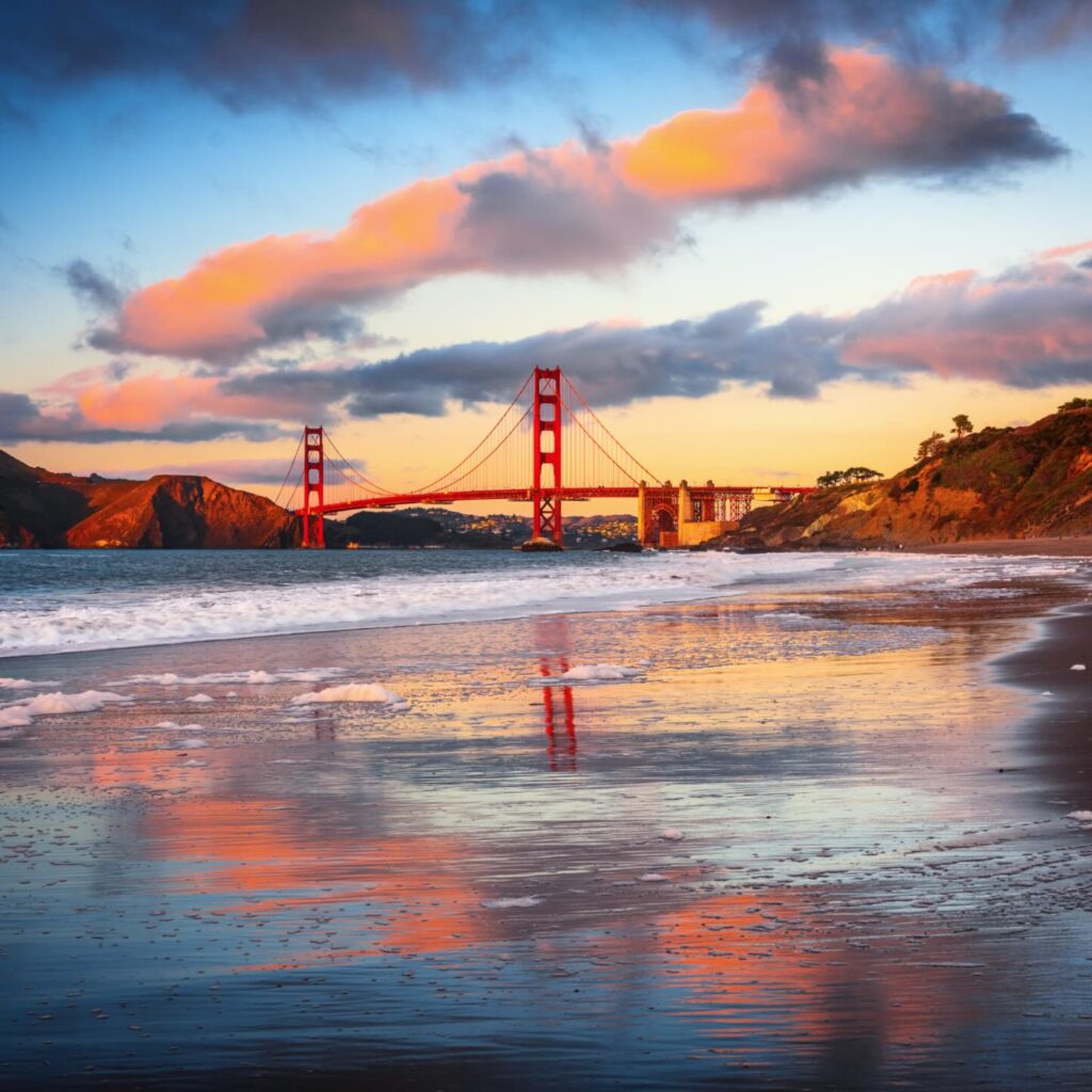 Golden Gate Bridge viewed from Baker Beach during sunset with waves on the shore