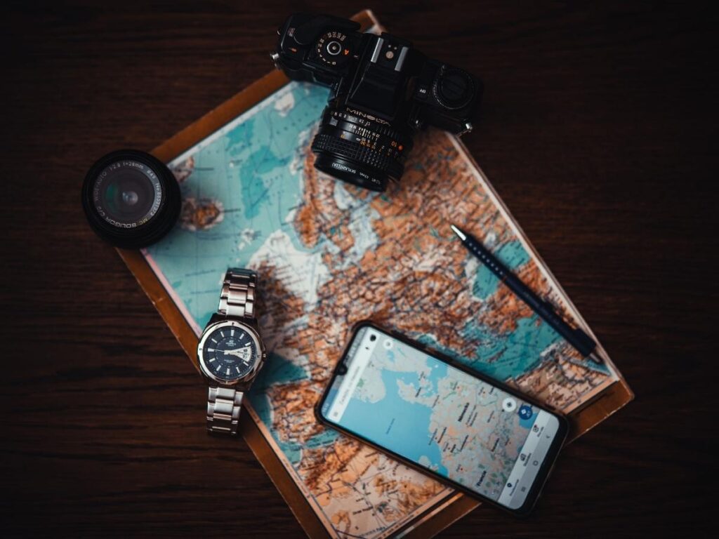 Woman using smartphone with travel apps while planning trip with map and passport