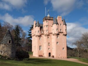 Pink Craigievar Castle surrounded by green hills in Aberdeenshire Scotland