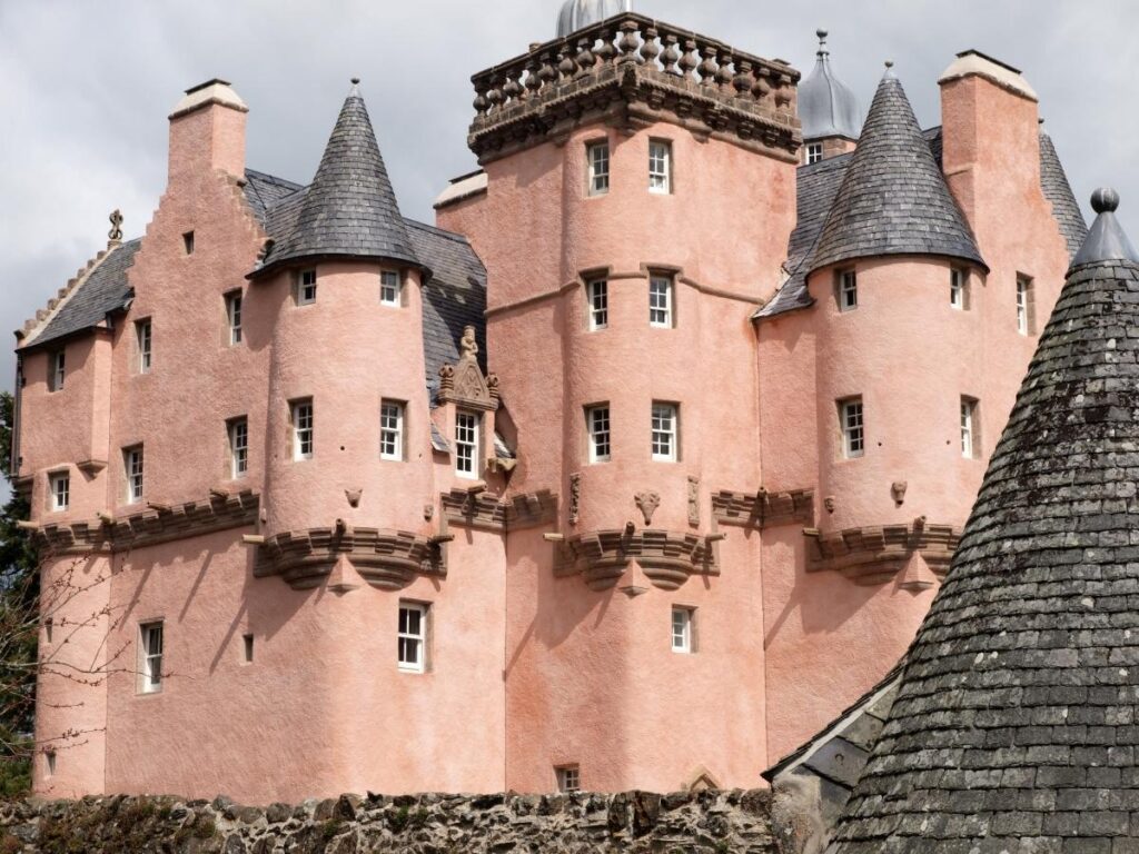 Salmon pink Craigievar Castle with turrets against blue sky in Scotland