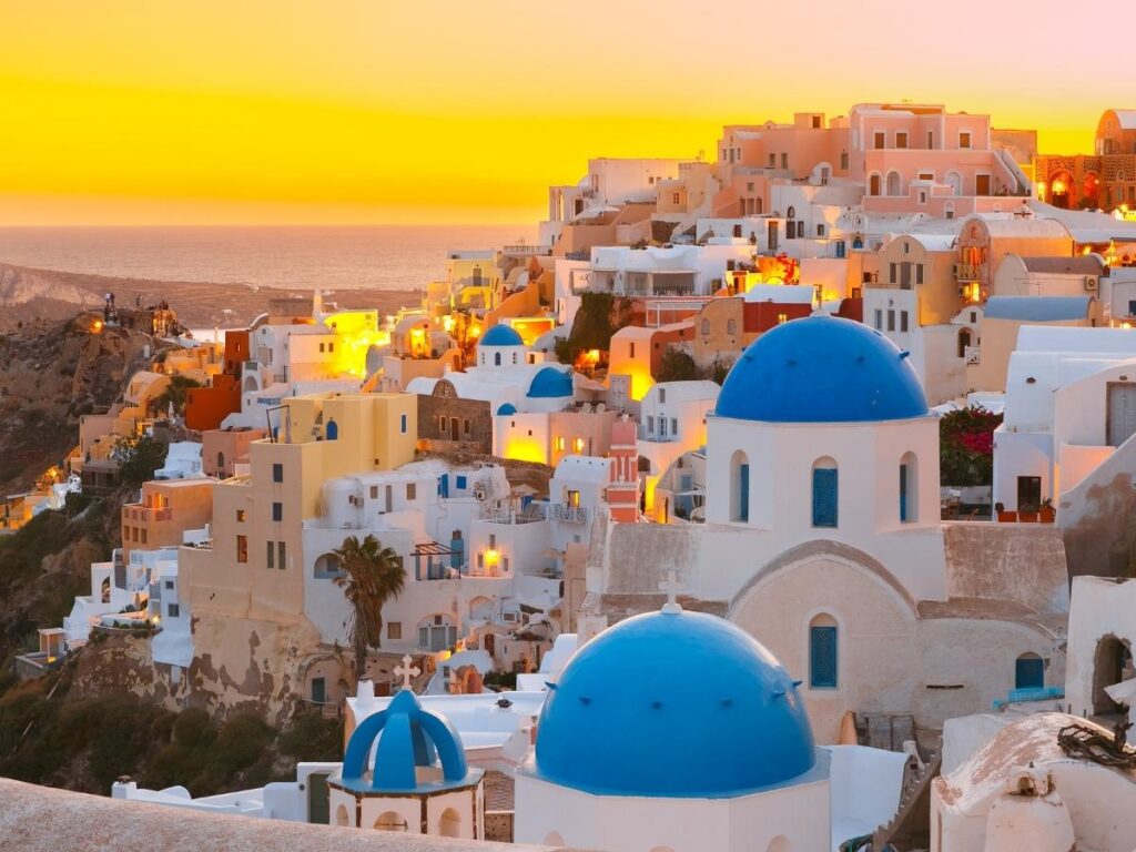 Photographer capturing sunrise views over white buildings in Santorini Greece during golden hour