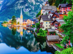 Colorful houses reflected in Lake Hallstatt with Alpine mountains in background, Austria