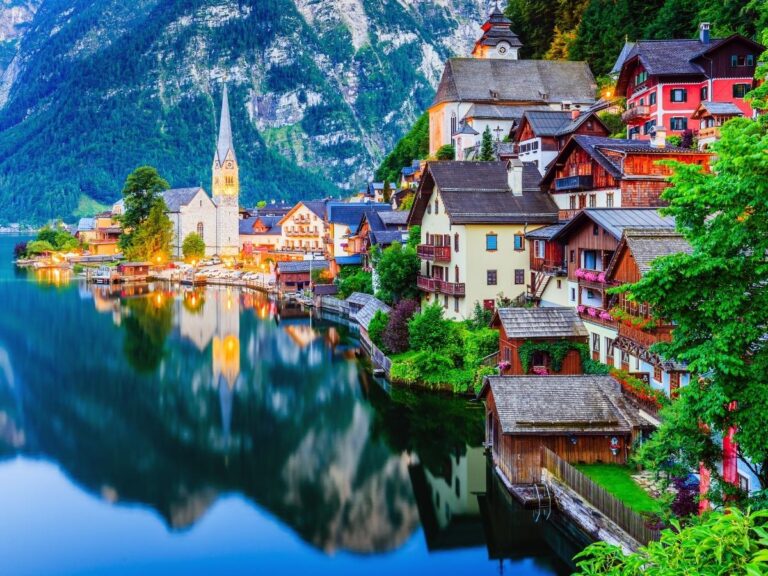 Colorful houses reflected in Lake Hallstatt with Alpine mountains in background, Austria